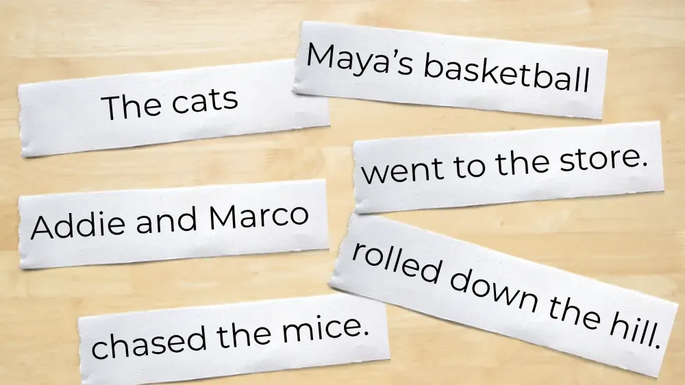 Pieces of paper with phrases for sentence building, including 'The cats', 'Addie and Marco', 'chased the mice', 'Maya's basketball', 'went to the store', and 'rolled down the hill'.