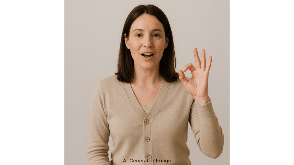 A woman holds up her left hand, pressing her pointer finger to her thumb while speaking. 