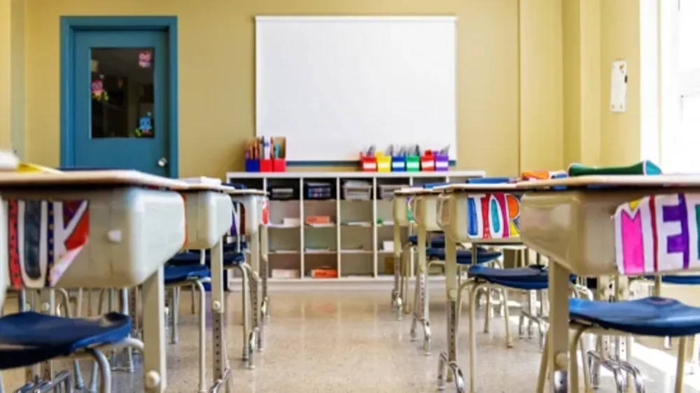 Empty classroom with desks and chairs arranged in rows facing a whiteboard.