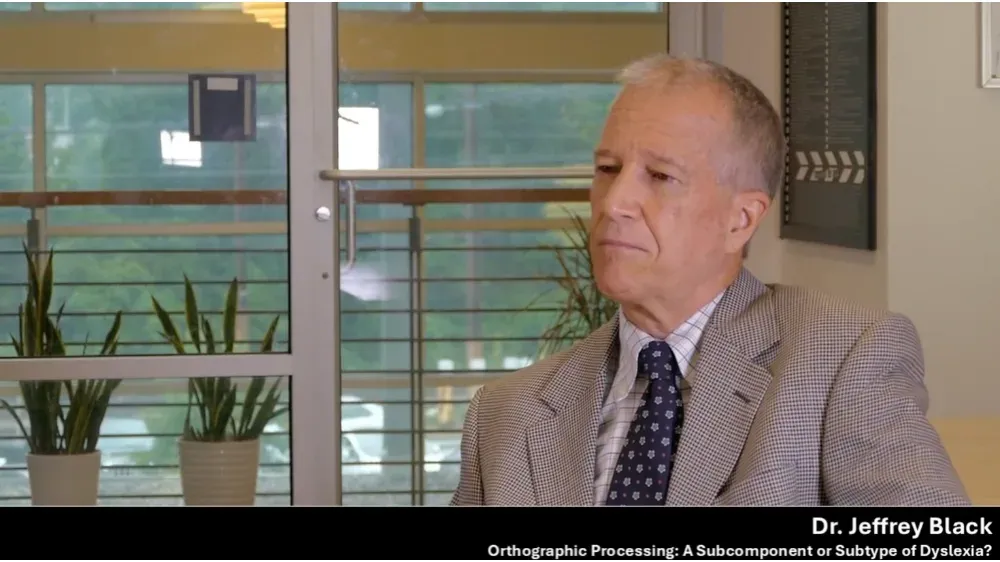 Dr. Jeffrey Black, a distinguished professor in a suit and tie, looks thoughtfully to the side.